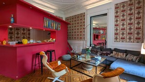 A modern living room with a red accent wall, a coffee table, a sofa, and a bar area with stools. - Apartment with terrace, garden and WIFI in the historic heart of Angoulême (Angoulême)