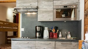 A modern kitchen with grey cabinetry, a built-in oven, and a coffee maker.