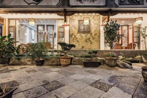 Une cour intérieure agrémentée de plantes en pot, dotée d’un sol en pierre et de portes en bois d’époque.