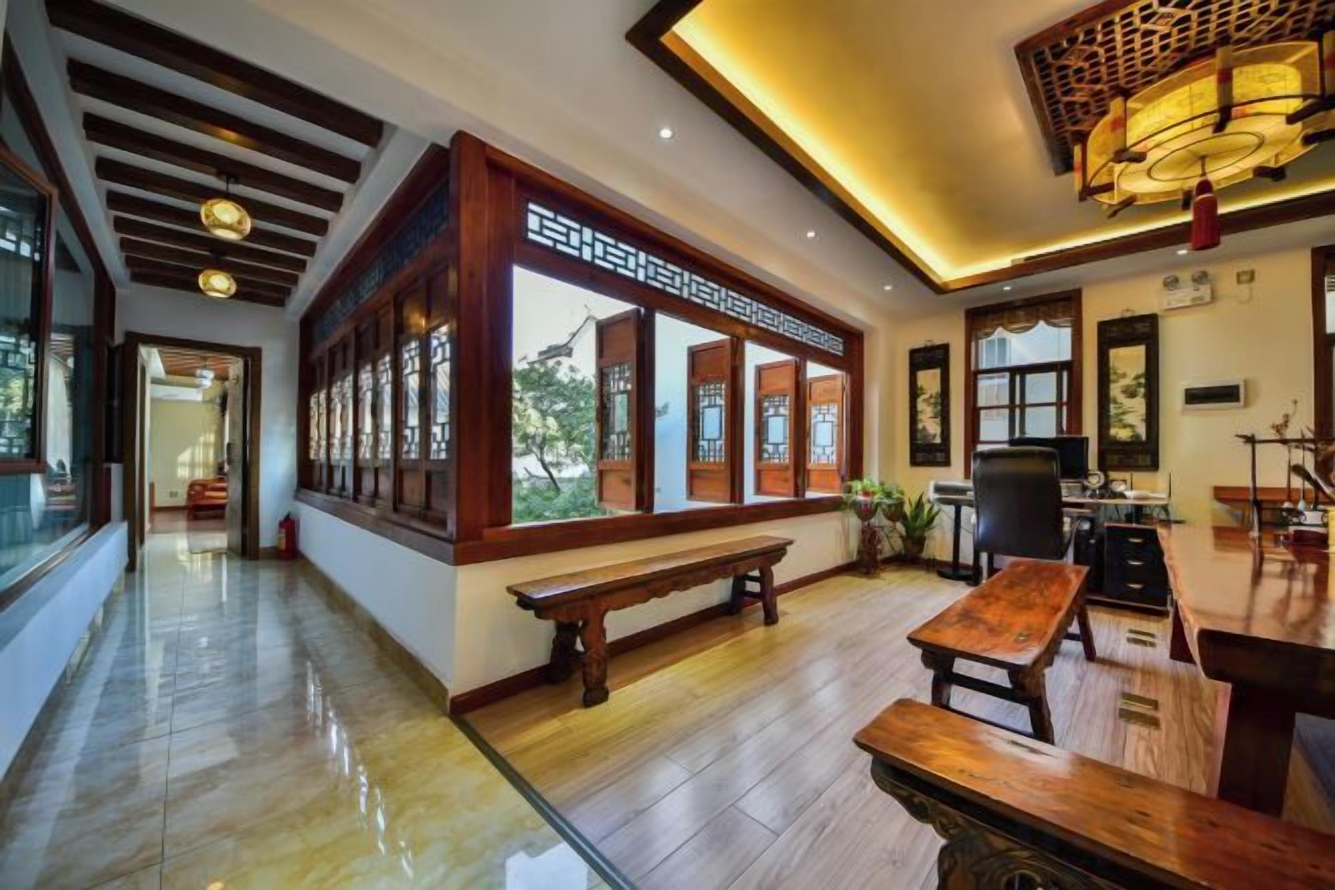 A traditional interior with a wooden bench, a table, and a view through large windows.