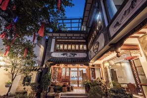 A traditional courtyard with a wooden gate, potted plants, and a tiled roof.