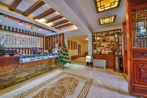 A hotel lobby with a reception desk, a Christmas tree, and traditional decor.