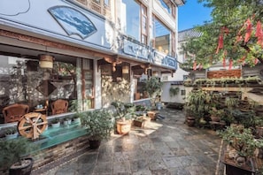 A courtyard with potted plants, outdoor seating, and a building facade with a balcony.