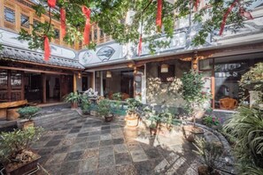 Une cour dotée d’une architecture traditionnelle, agrémentée de plantes en pot et décorée de rouge.