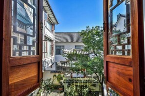 A traditional courtyard with a wooden gate, a tiled roof, and a small pond.