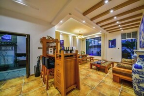 A spacious living area with a wooden bar, seating, and large windows. - Qianbaidu Boutique Inn (Dali City)