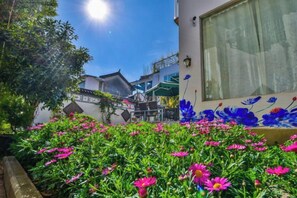 A building with a window and a flower bed in the foreground. - Qianbaidu Boutique Inn (Dali City)
