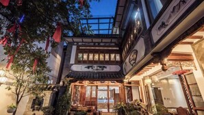 A traditional building with a wooden entrance, potted plants, and hanging decorations. - Qianbaidu Boutique Inn (Dali City)