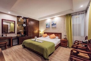 A hotel room with a bed, wooden furniture, a desk, a mirror, and artwork on the wall. - Qianbaidu Boutique Inn (Dali City)