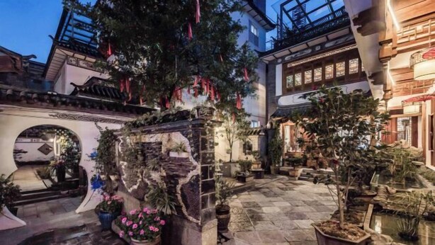 A courtyard with stone flooring, potted plants, and traditional architecture. - Qianbaidu Boutique Inn (Dali City)