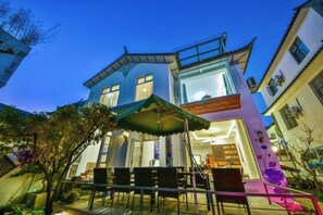 A two-story building with a balcony and outdoor seating area. - Qianbaidu Boutique Inn (Dali City)