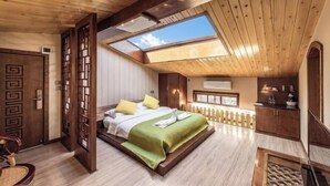 A bedroom with a skylight, wooden ceiling, and a bed with a green blanket. - Qianbaidu Boutique Inn (Dali City)