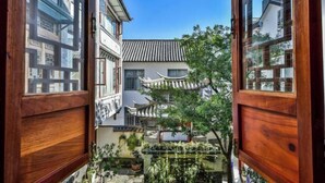 A traditional courtyard with wooden doors, tiled roofs, and potted plants. - Qianbaidu Boutique Inn (Dali City)
