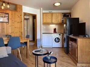 Un espace de vie compact comprenant un coin repas, une cuisine et un téléviseur.