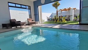 Una piscina con sillas de descanso y una zona de terraza.
