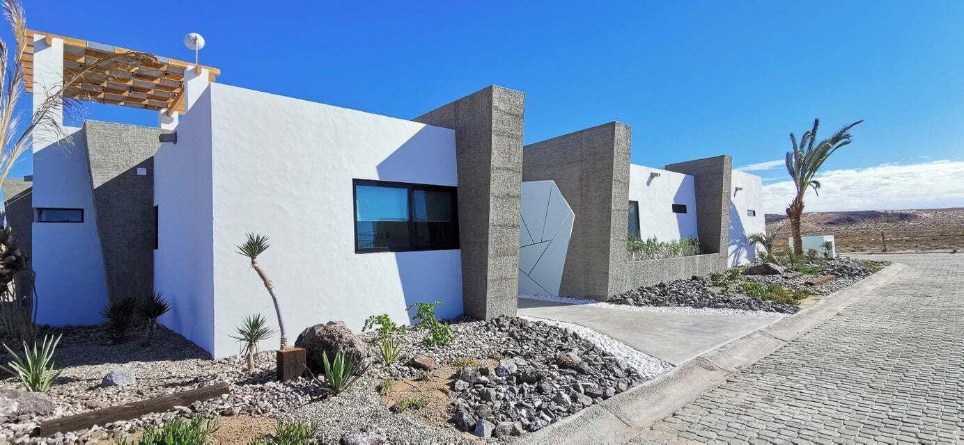 A modern building with a white facade, large windows, and a stone base.