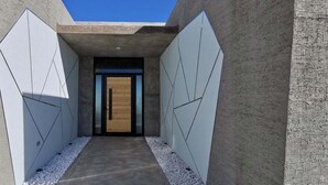 Un pasillo estrecho con paneles geométricos en la pared y una puerta de madera al final.