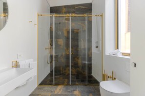 Uma casa de banho moderna com cabine de duche em vidro, banheira branca e sanita.