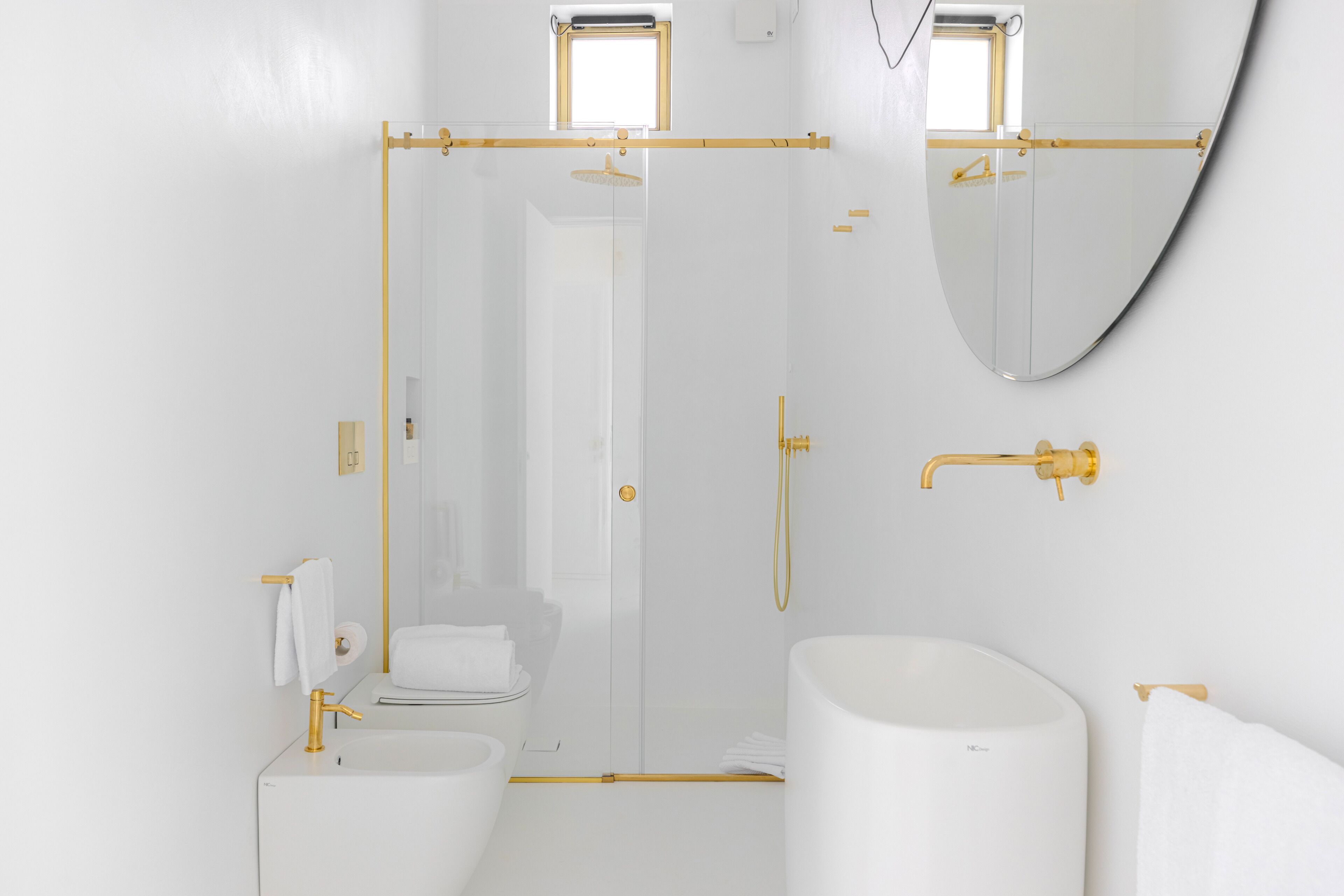 Une salle de bain moderne avec une douche à parois de verre, un lavabo blanc et un grand miroir.