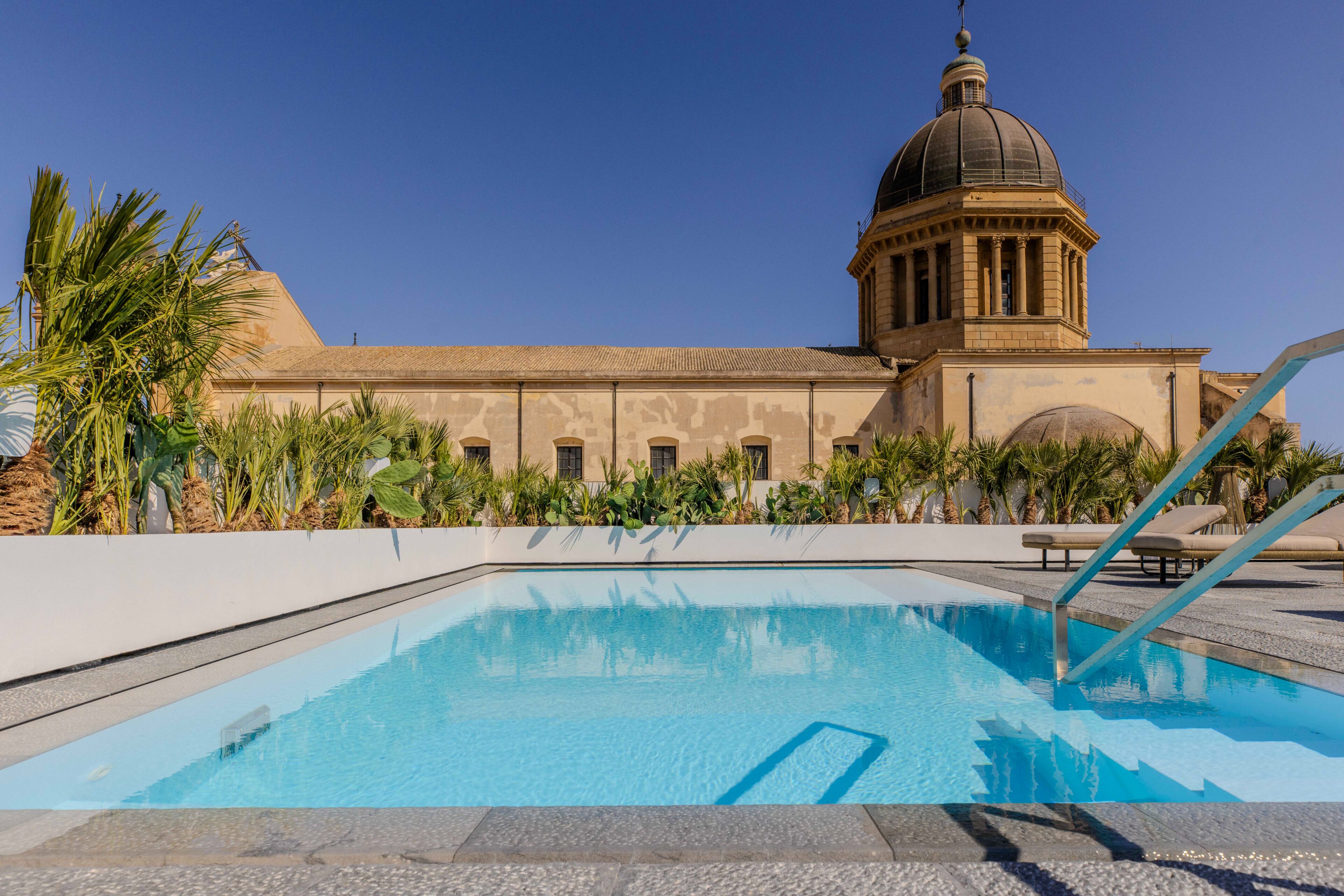 Piscina com vista para um edifício com cúpula e colunas.