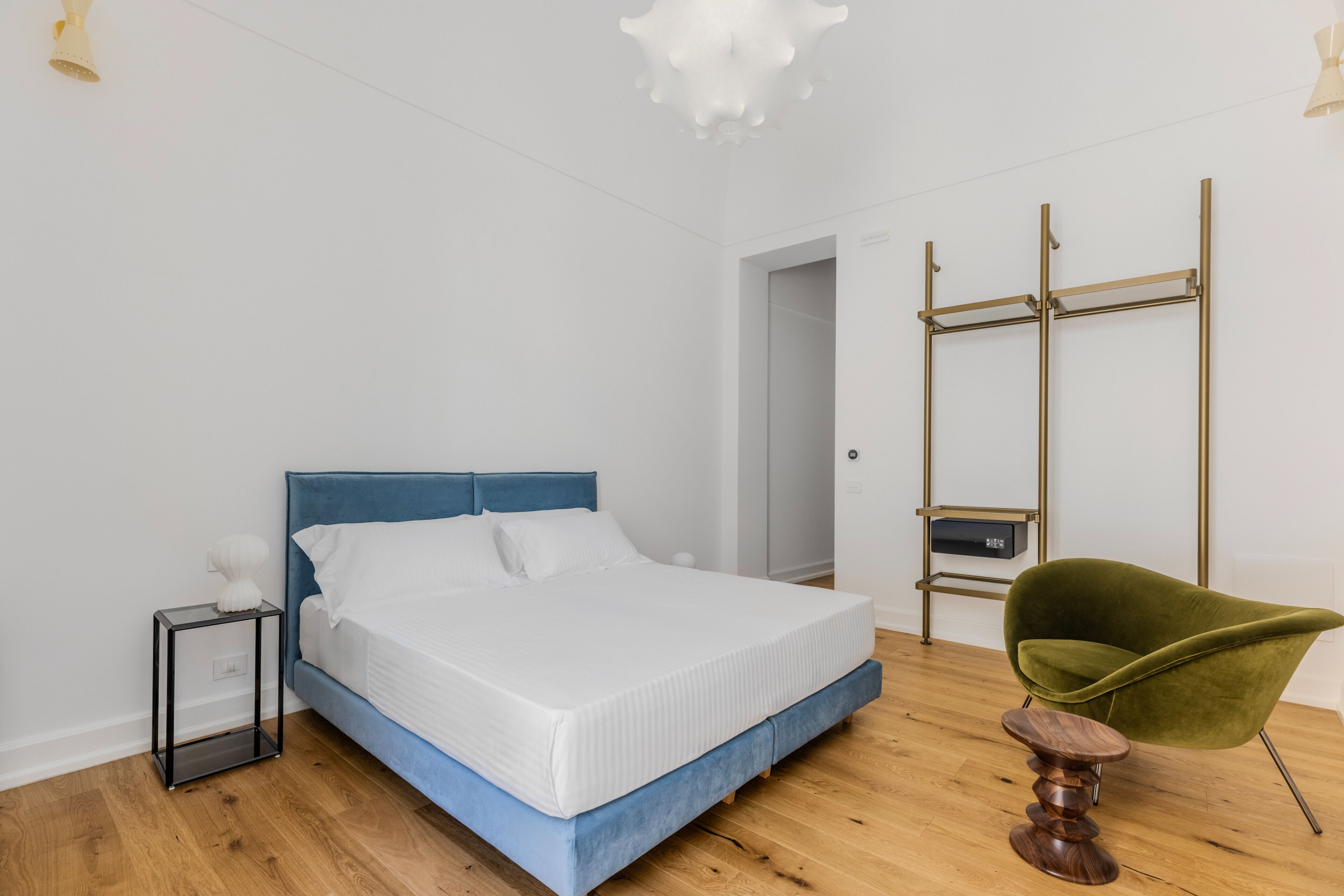 A bedroom with a bed, bedside table, chair, and a wardrobe.