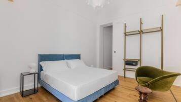 A bedroom with a bed, bedside table, chair, and a wardrobe.