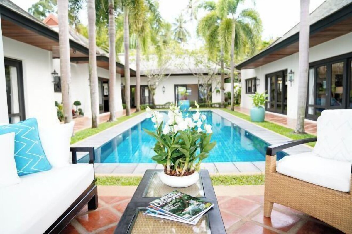 A poolside area with lounge chairs, a small table with magazines, and a flower arrangement.
