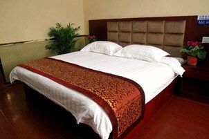 Una cama bien hecha con un edredón estampado, un cabecero y una mesita de noche con una planta en maceta.