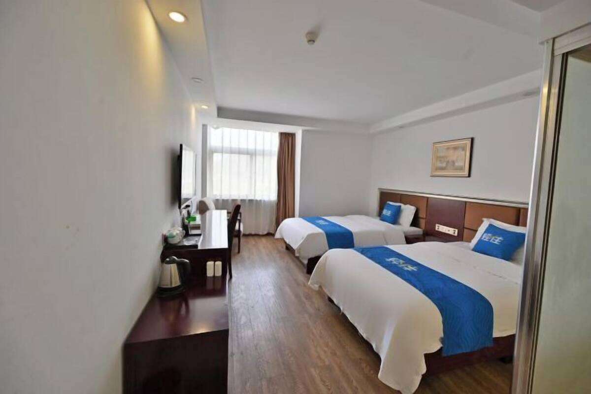 A hotel room with two beds, a desk, and a chair.