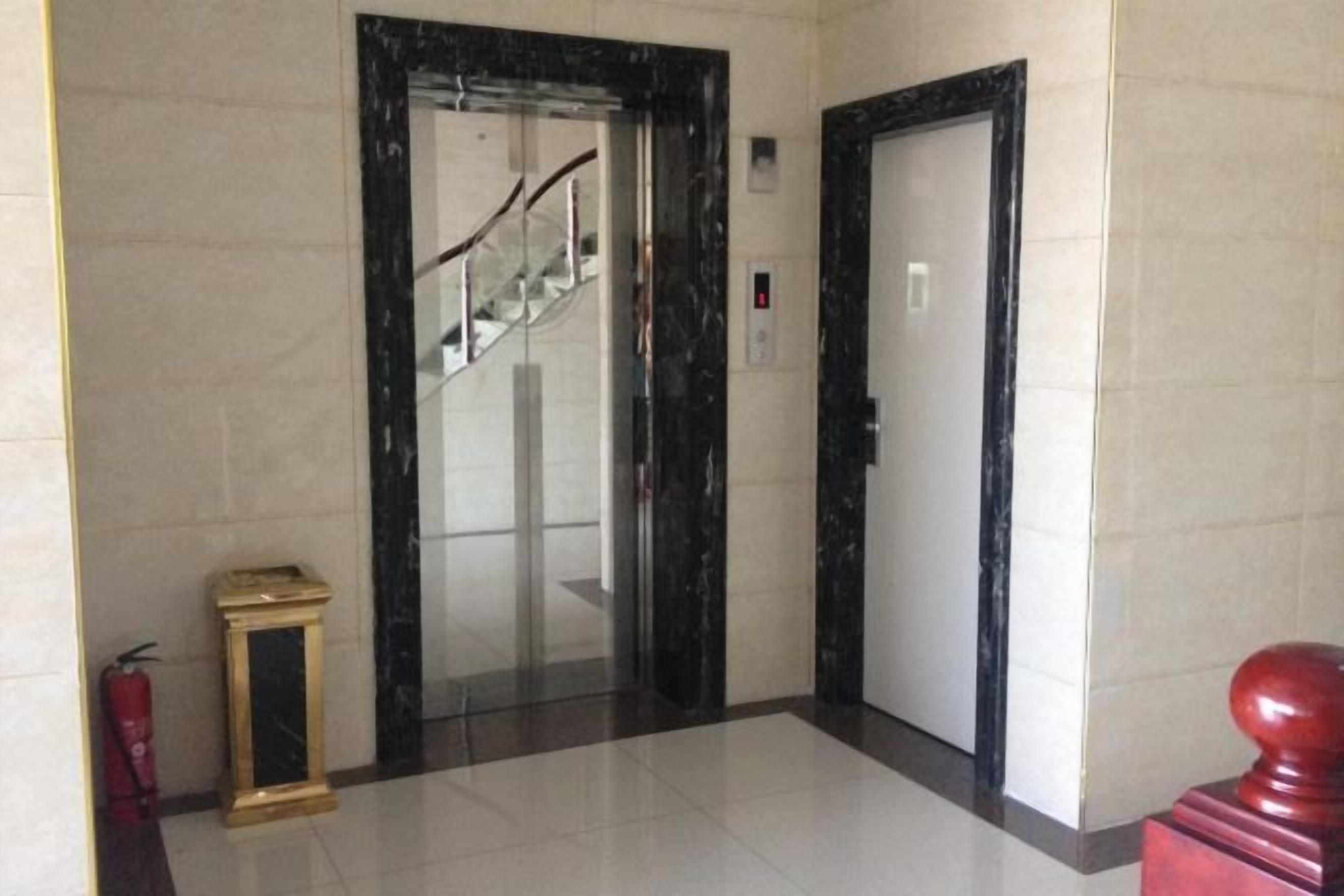 An elevator with a glass door, a fire extinguisher, and a red object on the right.