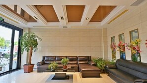 A modern lobby with a leather sofa, potted plants, and a large window. - Jinzhai Oriental Business Hotel (Jinzhai)