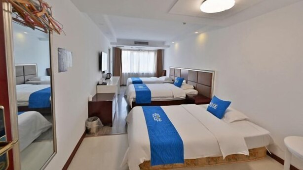 A hotel room with three beds, a desk, a mirror, and a window with curtains. - Jinzhai Oriental Business Hotel (Jinzhai)