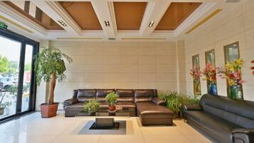 A spacious living area with a large sectional sofa, a coffee table, and potted plants.
