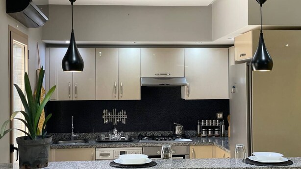 A modern kitchen with granite countertops, stainless steel appliances, and pendant lighting.