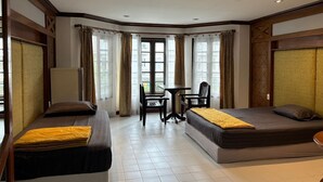 Een hotelkamer met twee bedden, een tafeltje en stoelen.