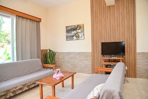 A living room with a sofa, a coffee table, a TV, and a potted plant. - Room-kritos Apartments-one Bedroom (Argaka)