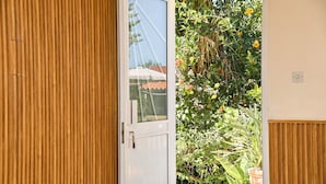 Una puerta de madera que da a un jardín con diversas plantas y flores.