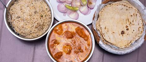 A table with various dishes including rice, a curry, sliced onions, and a flatbread.