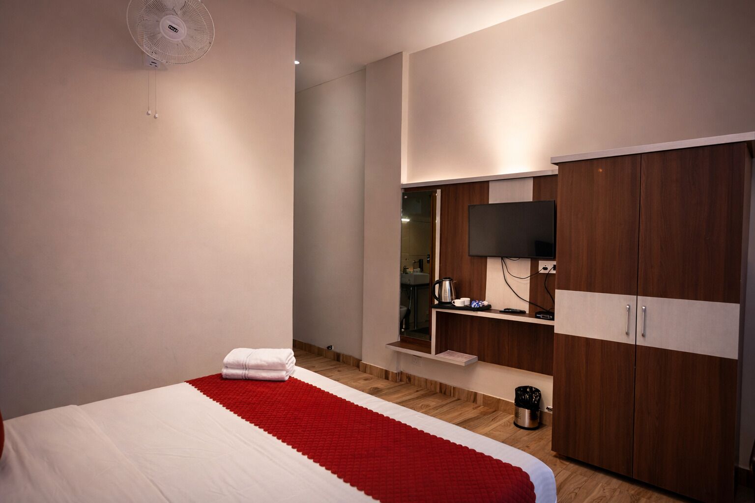 Habitación de hotel con cama, televisor, armario y una pequeña zona de kitchenette.