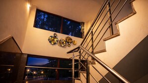 A modern staircase with metal railings, a large window with a view of the outside, and decorative wall art.