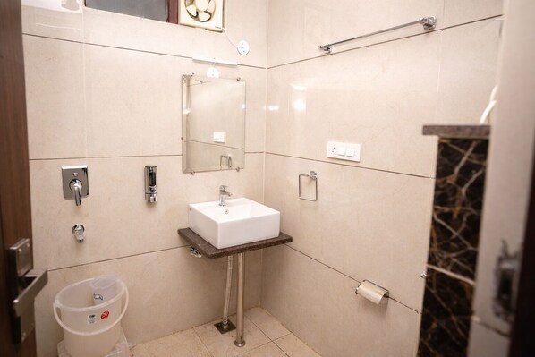 A modern bathroom with a white sink, mirror, towel rack, and a trash bin. - HOTEL DALHOUSIE VIEW (Dalhousie)