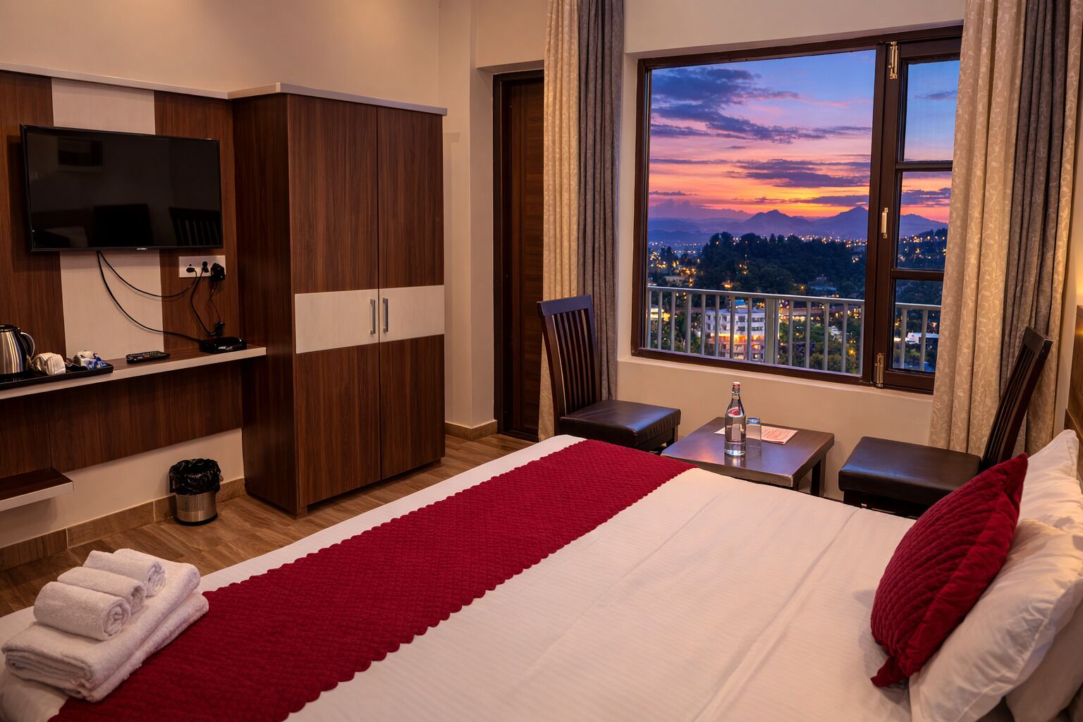 A hotel room with a bed, a TV, a wardrobe, a desk, a chair, and a window with a city view.