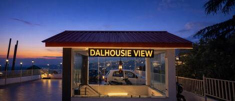 A small, glass-walled structure with a metal roof labeled 'DALHOUSESIE VIEW' and a car parked inside.