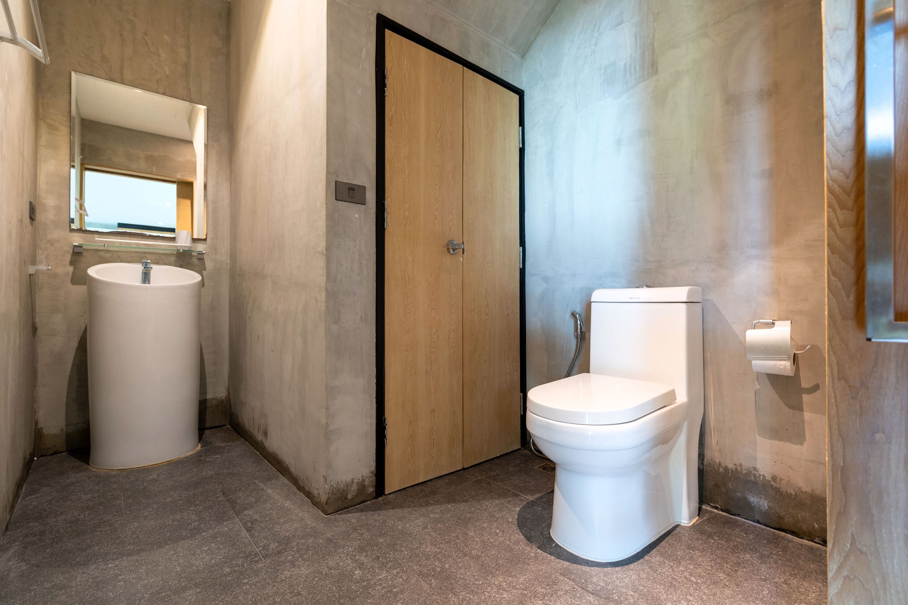 A bathroom with a wooden door, a white sink, and a toilet.