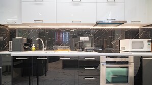 A modern kitchen with a sleek design, featuring a black marble backsplash, stainless steel appliances, and a built-in oven. - Cozy Studio at Vyronas for 2 pers by MPS (Vironas)