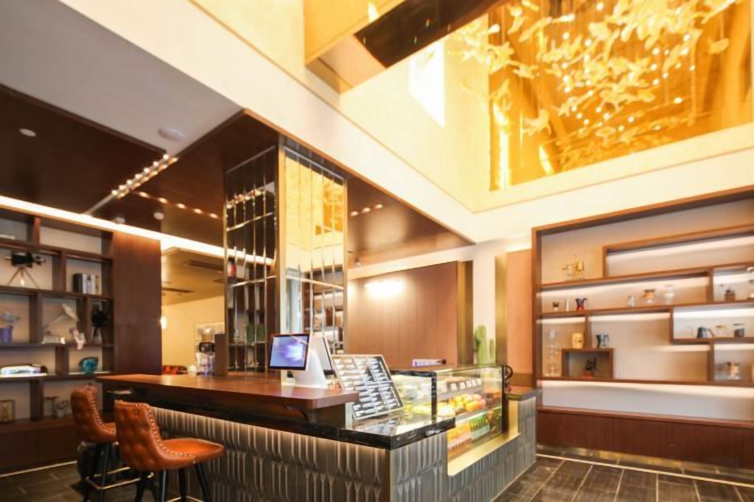 Een hotelhal met een receptiebalie, een bar en etalages.