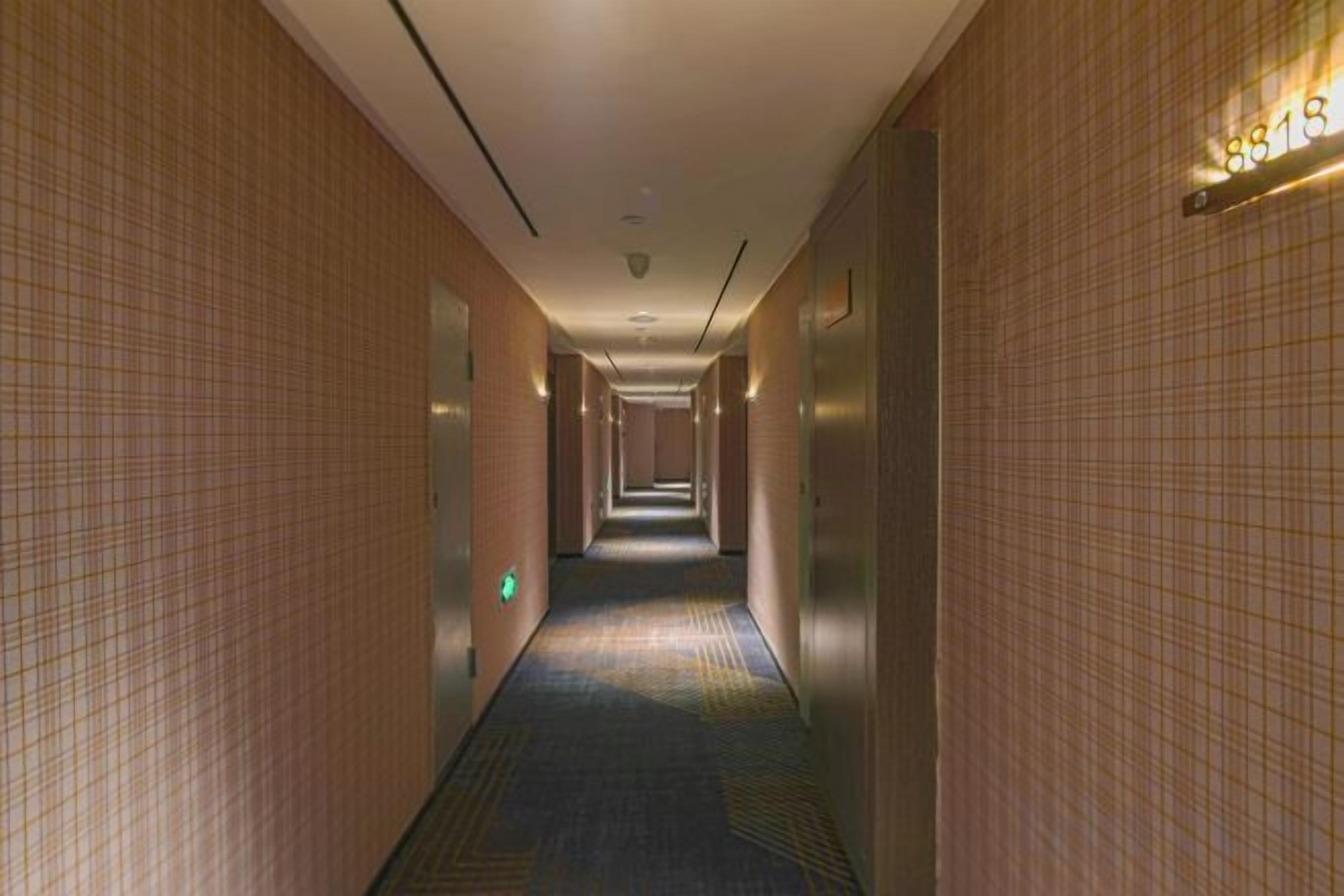 Un pasillo de hotel con un mostrador de recepción, un escritorio de información y un cartel que indica la habitación 8518.