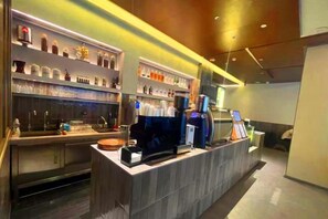Eine moderne Bar mit einer Theke, Regalen voller Flaschen und einer Kaffeemaschine.