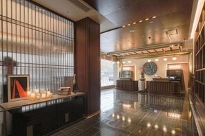 Rebuda d'hotel amb una taula de recepció, una zona de seients amb espelmes i una finestra gran.