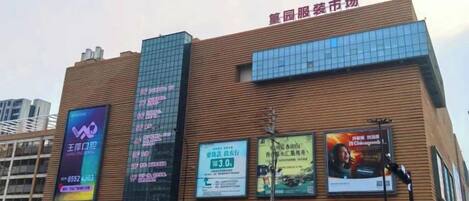 A building with multiple advertisements on its facade, a large sign at the top, and a busy street in front.